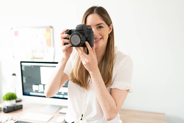 Mulher caucasiana atraente e fotógrafo freelance segurando uma câmera profissional e sorrindo - Foto, Imagem
