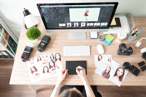 Top view of the workspace of a photographer with a camera, equipment, computer, prints, a graphic tablet and more. - 写真・画像