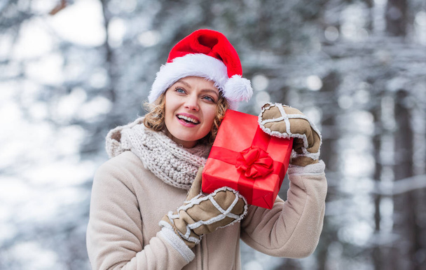 Teşekkür ederim. Kırmızı Noel Baba şapkalı kadın hediye kutusunu tutuyor. Boks günü. Kış alışverişi. hediye ve sürpriz konsepti. Herkese mutlu noeller dilerim. Yeni yılınız kutlu olsun. Noel tatili. Hediye zamanı. - Fotoğraf, Görsel
