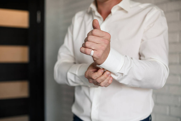 Мужчина бизнесмен застегивает пуговицу на рукаве белой рубашки - Фото, изображение