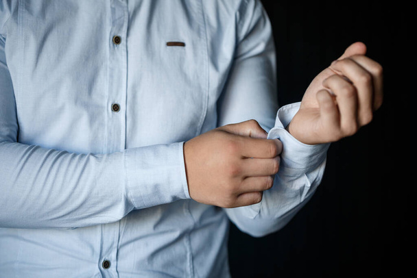 Erkek işadamı düğmelerini beyaz bir gömleğin koluna iliştiriyor. - Fotoğraf, Görsel