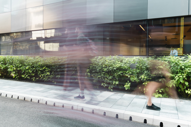 motion blur of people walking on urban street near modern building  - Photo, Image