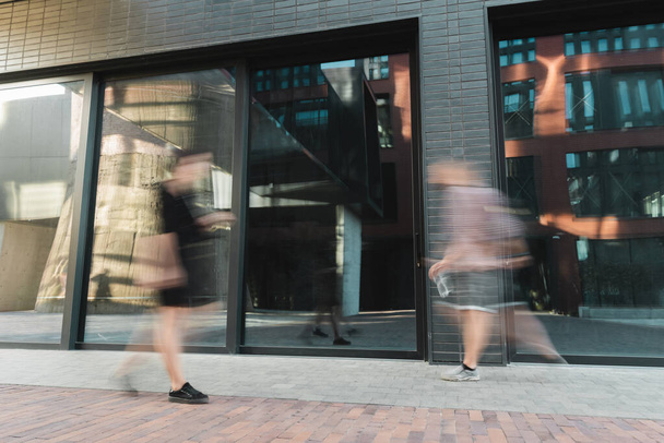 motion blur of citizens walking on modern street near building  - Фото, изображение