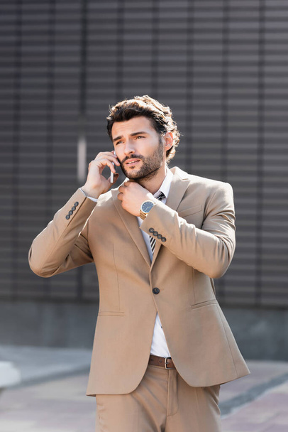 confident businessman talking on smartphone outside  - Фото, изображение