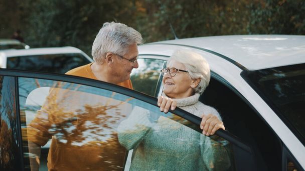 Starsza para kupiła nowy samochód. Stojąc blisko drzwi i kobieta trzymając klucze - Zdjęcie, obraz