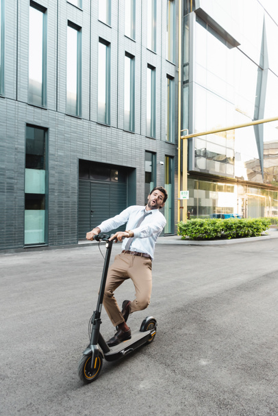 hombre de negocios sorprendido en desgaste formal montar scooter eléctrico cerca de la construcción  - Foto, imagen