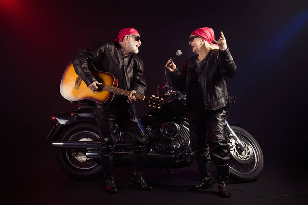 Full body photo of aged cool bikers man lady couple chopper moto rock festival play guitar sing famous hit show horns wear trendy rocker leather outfit isolated black color background - Photo, image