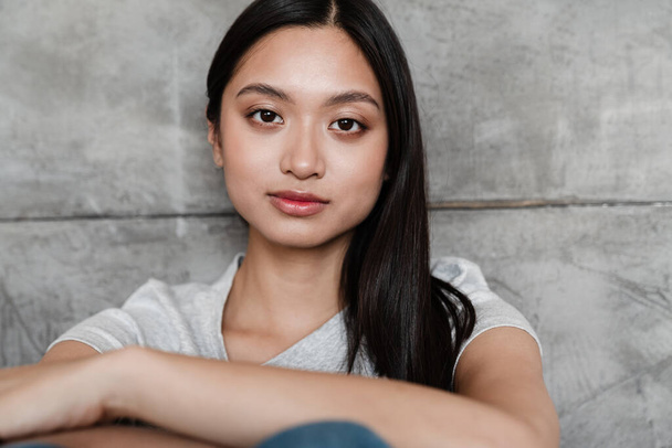 Image of beautiful asian girl looking at camera while sitting indoors - Valokuva, kuva