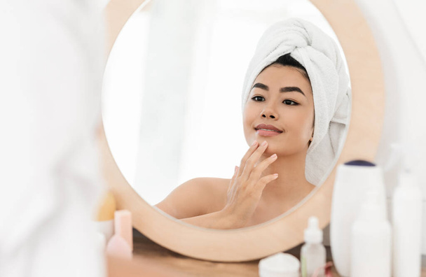 Beautiful asian young woman applying face cream - 写真・画像
