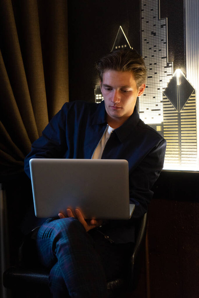 young man sits at a table in front of a laptop. man working at laptop - Foto, afbeelding