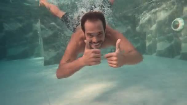 Imágenes submarinas del hombre de vacaciones sumergiéndose en el agua de la piscina sonriendo a la cámara - Metraje, vídeo