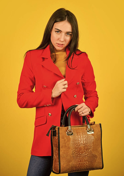 Stylish accessories. Beauty brunette. Fashionable woman in jacket. Fashion autumn winter. female trendy beauty. handbag and accessories. Trendy girl holding small leather bag in hand - 写真・画像