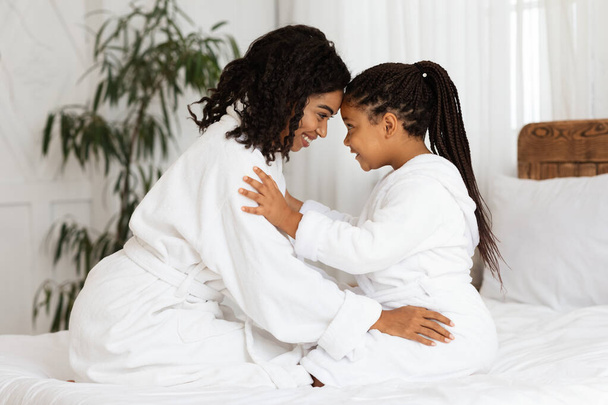 Kochająca czarna matka nawiązująca więź ze swoją małą córeczką w łóżku w domu - Zdjęcie, obraz
