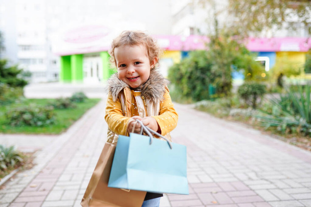 Piękna dziewczynka trzyma kolorowe torby na zakupy - Zdjęcie, obraz