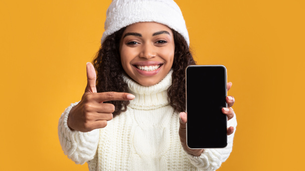 Zwarte vrouw toont blanco mobiele telefoon scherm - Foto, afbeelding