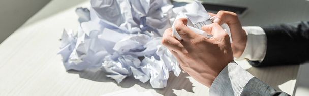 Vista cortada de homem de negócios com as mãos perto de pilha de papéis desmoronados no fundo borrado, banner - Foto, Imagem
