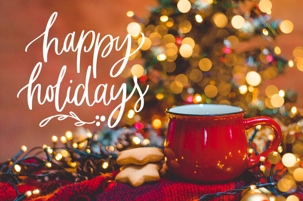 Piros bögre forró kávé karácsonyi lámpákkal, friss sütemény, krém, fahéj és szalma - Fotó, kép