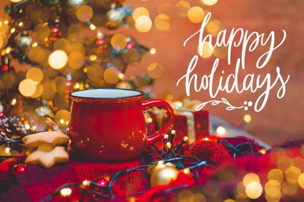 Červený hrnek horké kávy s vánočními světly, čerstvé sušenky, smetana, skořice a sláma - Fotografie, Obrázek