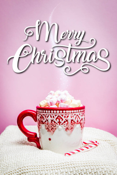 Pink white mug with marshmallows, Christmas tree, ornaments and Santa Claus hat on a marble and pink background - Photo, image