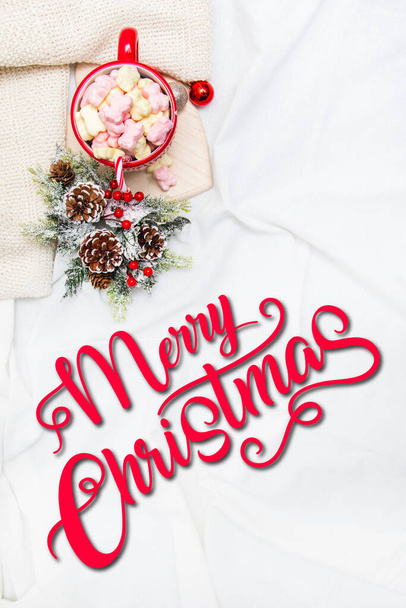 Tazza rossa con marshmallow e ornamenti invernali su fogli bianchi  - Foto, immagini