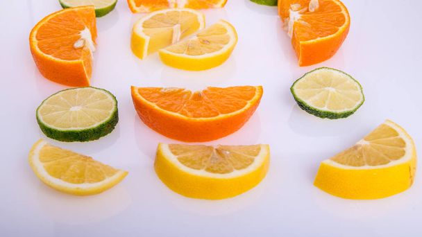 Лимон, апельсин, вапняні скибочки на білому тлі, ізольовані, креативне компонування, простір для тексту, вид зверху
 - Фото, зображення