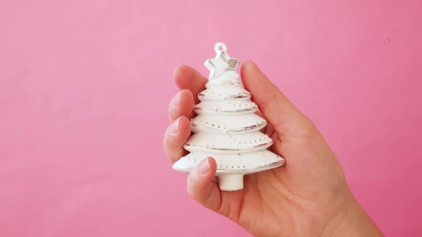 Egyszerűen minimális design női kéz tartó karácsonyi dísz fenyő fa elszigetelt rózsaszín pasztell színes trendi háttér. Karácsony újév december ideje ünnepi koncepció. Fénymásolási hely - Felvétel, videó