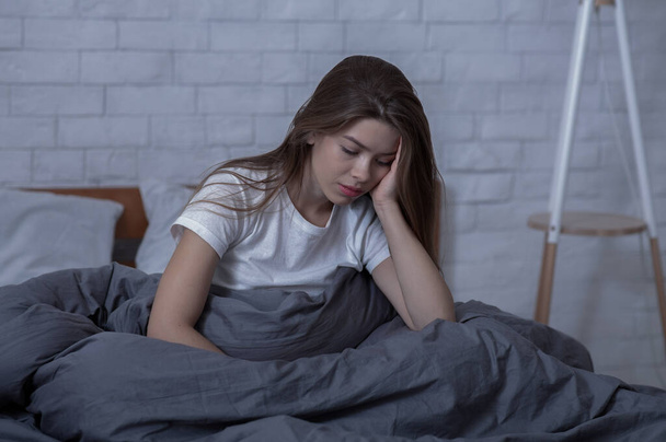 Talvi masennus käsite. Surullinen nuori nainen, jolla on kausiluonteinen mielialahäiriö tai masennus, istuu yksin sängyssään - Valokuva, kuva