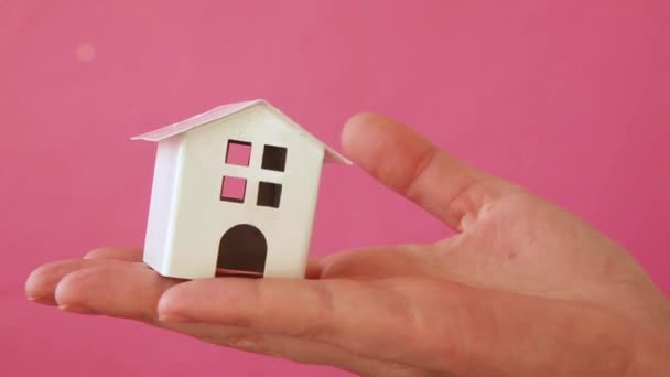 Simplesmente projete a mão da mulher feminina segurando a casa de brinquedo branca em miniatura isolada no fundo da moda colorido pastel rosa. hipoteca propriedade seguro sonho casa conceito - Filmagem, Vídeo