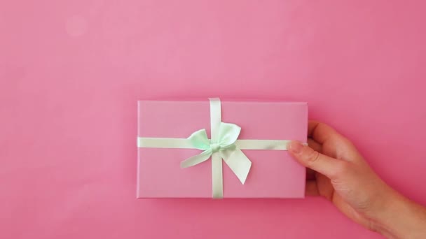 Egyszerűen design női nő kéz gazdaság rózsaszín ajándék doboz elszigetelt rózsaszín pasztell színes trendi háttér. Karácsony újév születésnapja Valentin-napi ünneplés jelen romantikus koncepció. Fénymásolási hely - Felvétel, videó