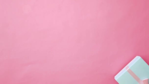 ピンクのパステルカラフルな流行の背景に隔離された青いギフトボックスを保持する女性の手を単に設計しなさい。クリスマスの新年のバレンタインのお祝いはロマンチックな概念を提示します。スペースのコピー - 映像、動画