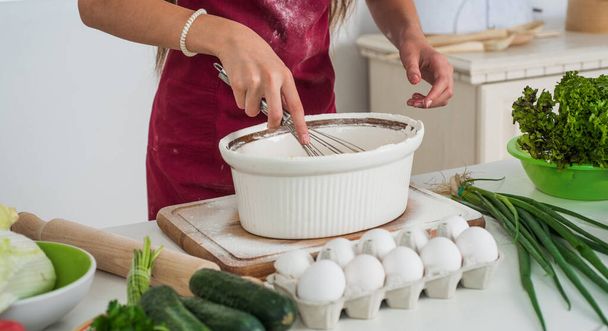 girl beating egg and flour for making dough with beater, professional skills - Foto, Bild