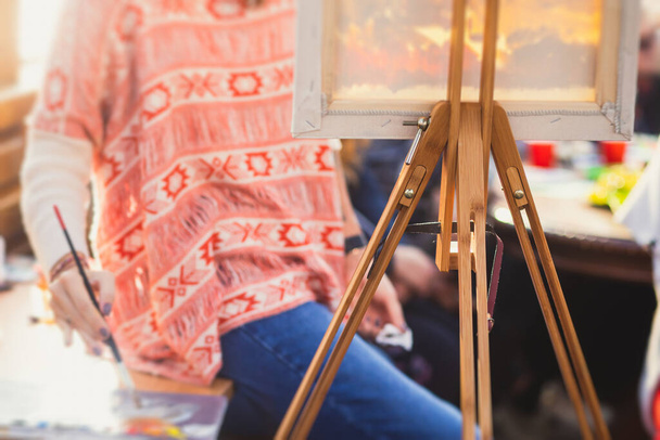 Process of painting, group class of adult talented students with paints easels, and canvases during lesson of watercolour painting outdoors, summer da - Foto, afbeelding