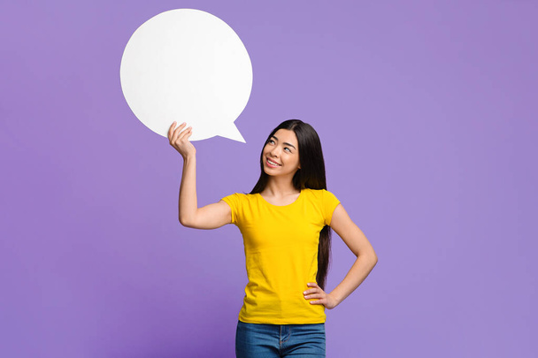 Nice Idea. Pensive asian woman holding and looking at blank speech bubble - Foto, afbeelding