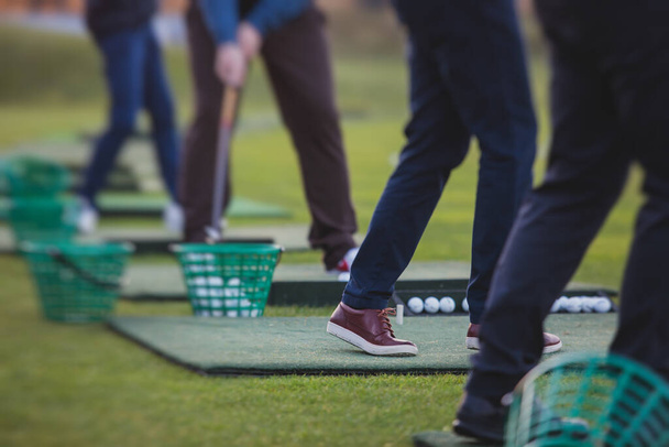 Gruppe von Golfspielern übt und trainiert Golfschwung auf der Driving Range, Männer spielen auf dem Golfplatz, Golfball im Golfkomplex Club Resort, Sommer sonnig da - Foto, Bild