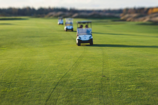 Golf electric cars riding on a golf course in the day, golf carts drive with golfers in resort clu - Fotó, kép