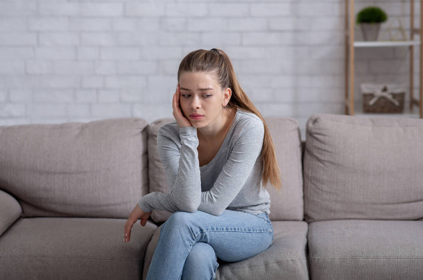 Концепция психического здоровья. Молодая женщина с депрессией на диване дома - Фото, изображение