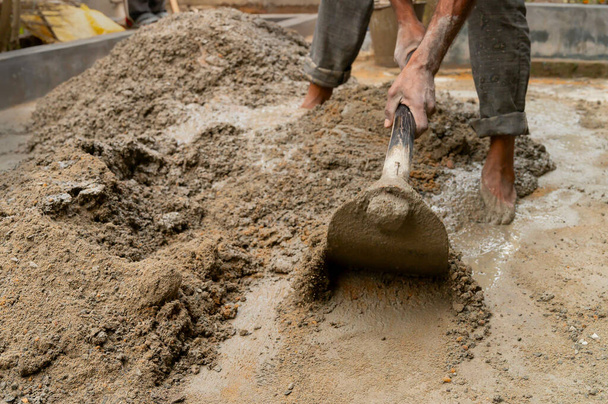 Індійська праця змішувала цемент і воду вручну на підлозі за допомогою лопати. Фотографія. - Фото, зображення