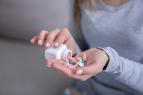 Committing suicide concept. Hopeless young woman pouring handful of pills from jar, closeup - Foto, immagini