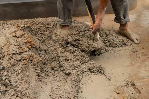 Індійська праця змішувала цемент і воду вручну на підлозі за допомогою лопати. Фотографія. - Фото, зображення
