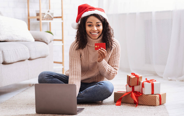 Vánoční nakupování. Černá dáma pomocí notebooku držící kreditní kartu - Fotografie, Obrázek