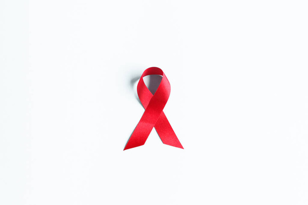 punainen AIDS-valistusnauha valkoisessa kirjassa. Maailman aids päivä ja terveydenhuollon ja lääketieteen käsite - Valokuva, kuva