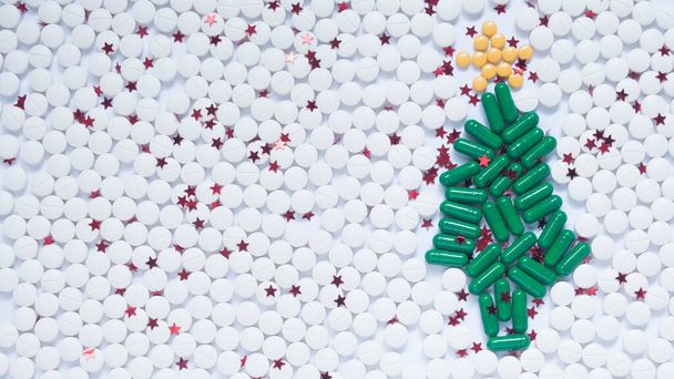 Χριστούγεννα και Ευτυχισμένο το Νέο Έτος θέμα για την υγειονομική περίθαλψη, ιατρική και φαρμακευτική έννοια. Πράσινο χριστουγεννιάτικο δέντρο, λευκό χιόνι και διακοσμητικό κίτρινο αστέρι γίνεται από χάπι / κάψουλα φάρμακο. Δημιουργική ιδέα. Αντιγραφή χώρου. - Φωτογραφία, εικόνα