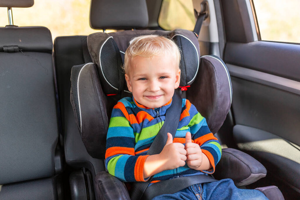 Little baby boy sitting on a car seat buckled up with his thumb up in the car. Children's Car Seat Safety - Foto, afbeelding