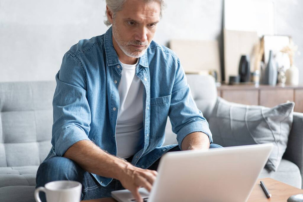 Middle-aged man working from home-office on laptop. - Φωτογραφία, εικόνα