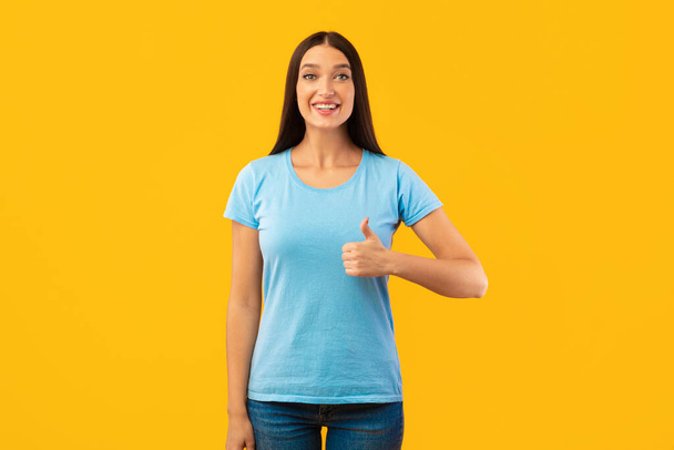 Happy woman gesturing thumbs up and smiling - Photo, Image
