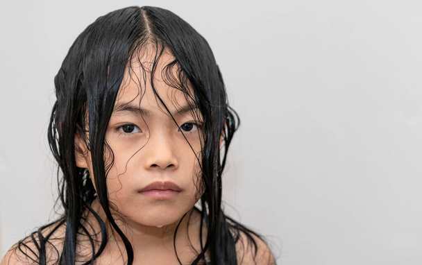 Portrét asijské dítě dívka po sprchování, vlasy a tělo stále mokré, nepředvídatelné nebo studené emoce, oči dívající se do kamery, ne úsměv. - Fotografie, Obrázek
