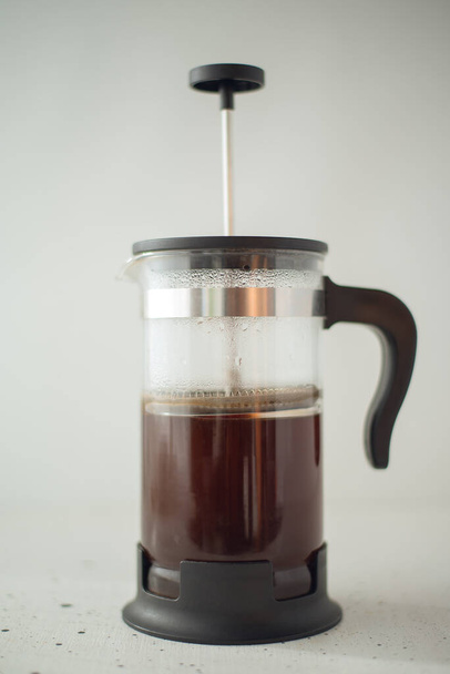 A classic French press with coffee in a light background. - Foto, Imagem