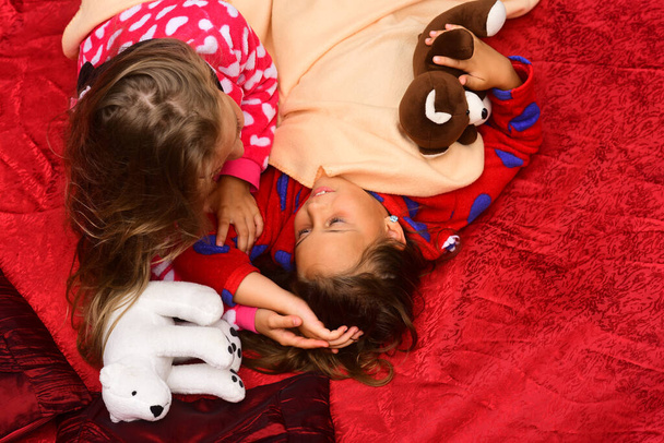 Kids in pajamas touch hair on dark background. - Zdjęcie, obraz