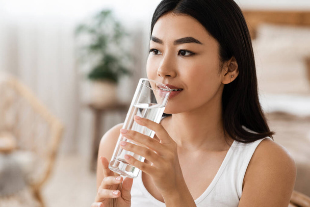 Young attractive asian woman drinking water, copy psace - Foto, imagen