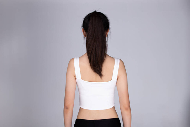 Back rear side view of Asian people present Hair style of black pony tail straight and wrap hair of woman in sport bra fitness dress, studio lighting gray background isolated half body - Φωτογραφία, εικόνα